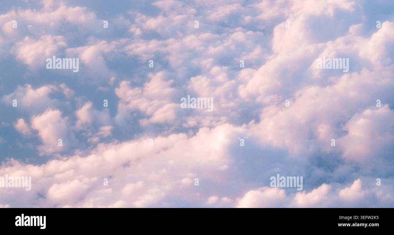 Fluffy pink clouds floating in blue sky Stock Photo