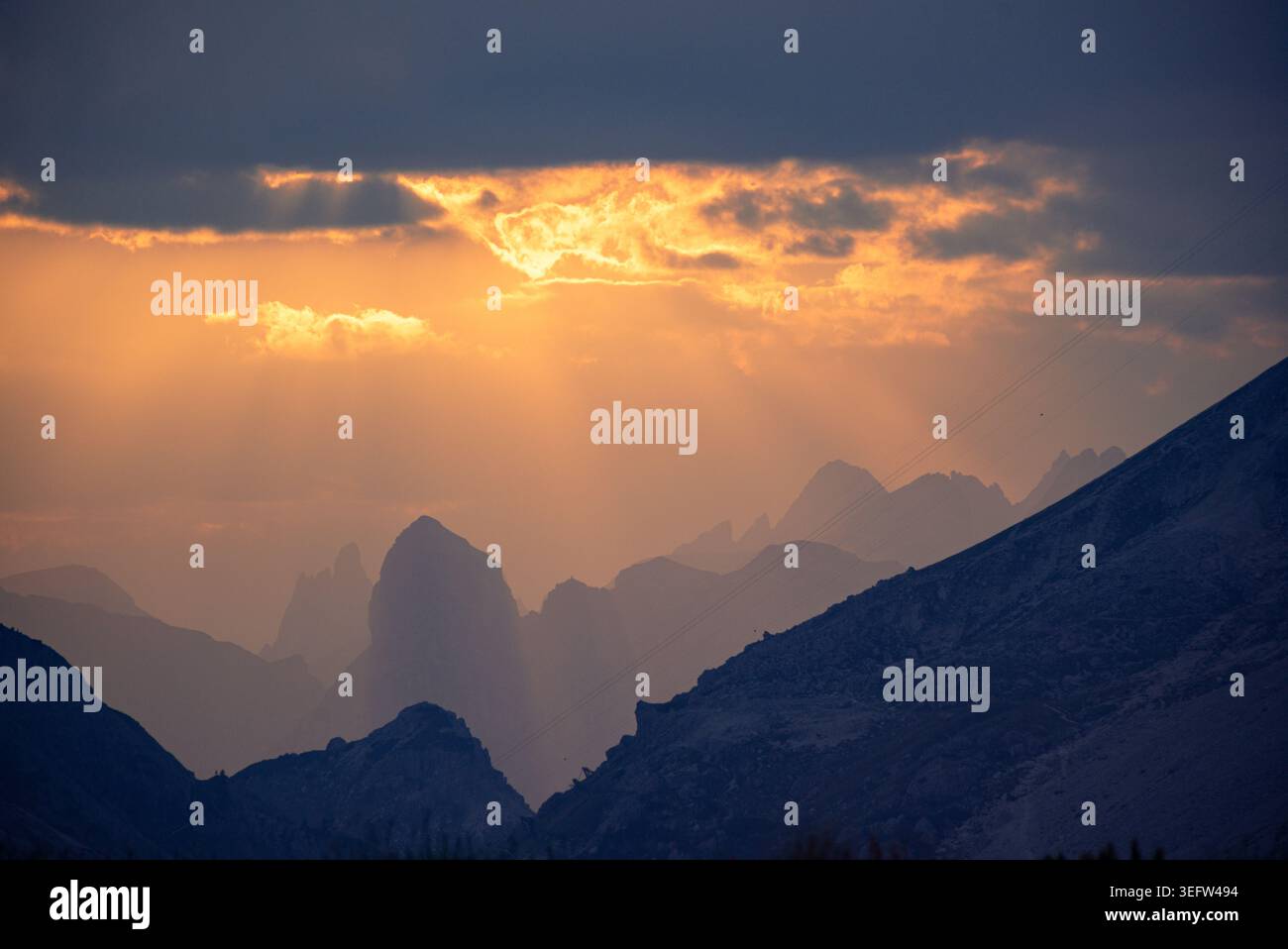 Sunbeams breaking through clouds over mountain landscape Stock Photo