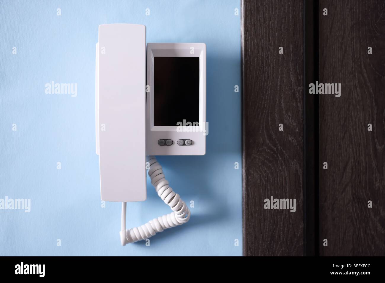 Modern intercom system with handset on light blue wall indoors Stock Photo