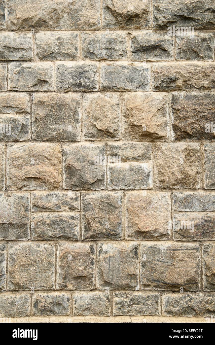 flat rustic grey stone masonry block wall, uniform square and rectangular stones with rough sandy finish, full frame background texture Stock Photo