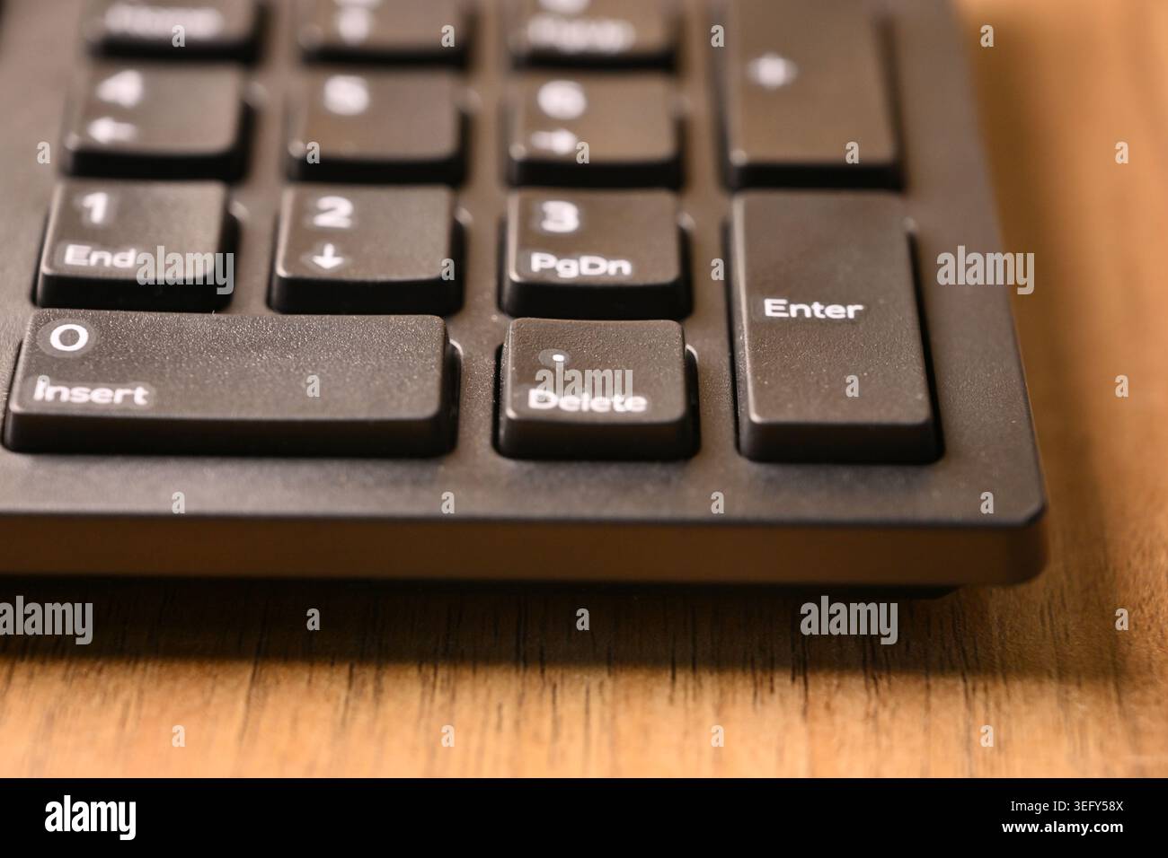 Angled Top View Macro Close-Up Black Computer Keyboard Highlighting Delete Key on Numeric Keypad on Blurred Tech Backgrounds Stock Photo