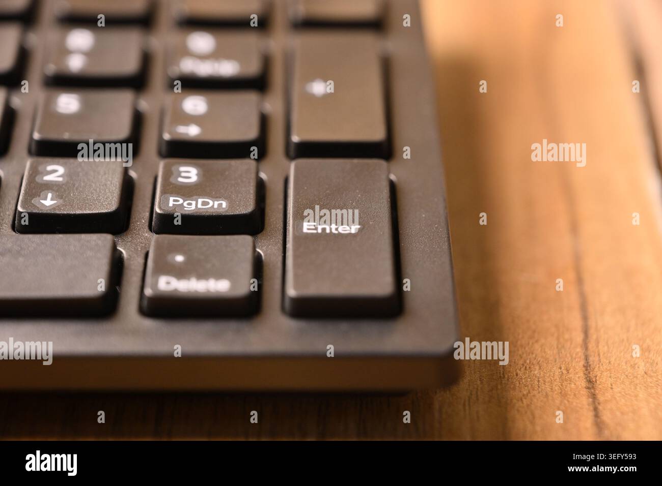 Angled Top View Macro Close-Up Black Computer Keyboard Highlighting Enter Key on Numeric Keypad on Blurred Tech Backgrounds Stock Photo