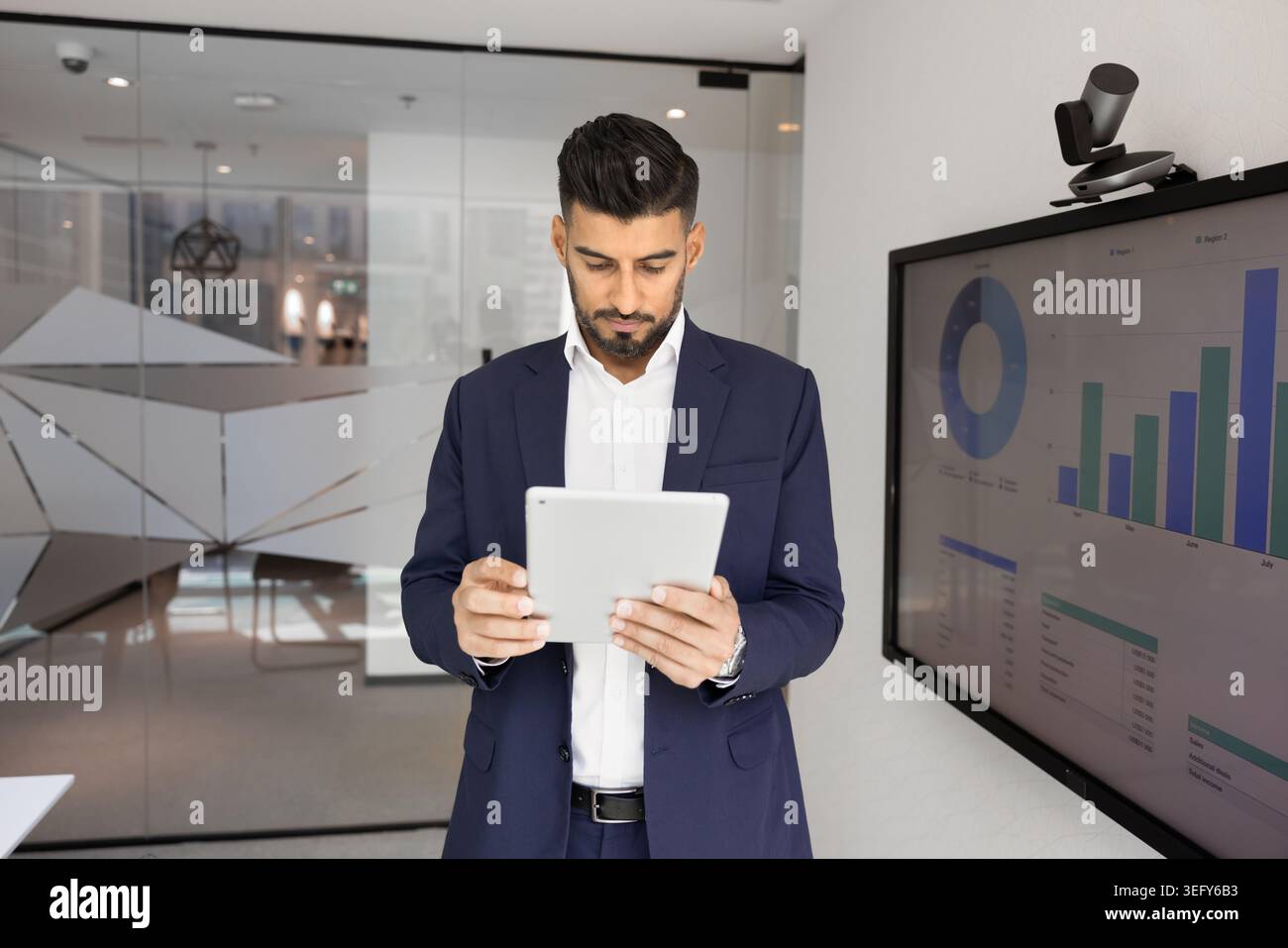 Indian businessman analyzing data on tablet in office Stock Photo