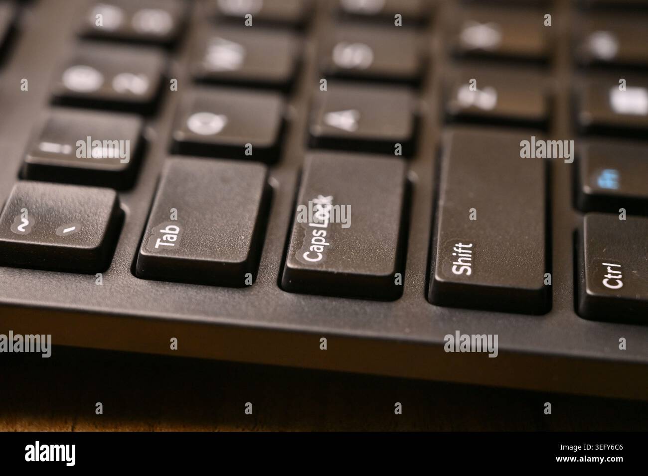 Side Angled Top View Macro Close-Up Black Computer Keyboard Highlighting Caps Lock Key on Blurred Tech Backgrounds Stock Photo