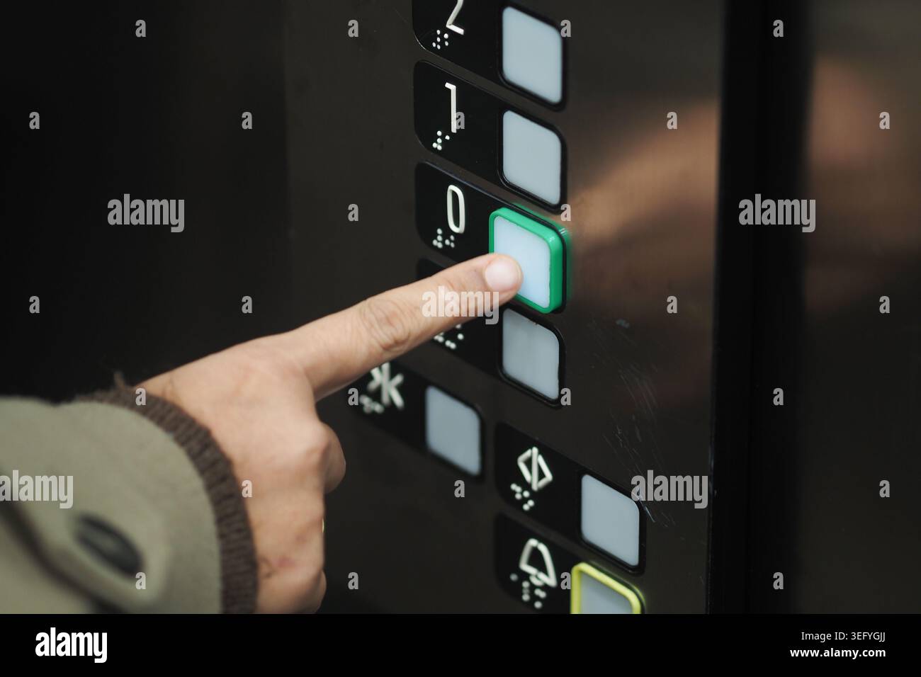 Hand presses elevator button for ground floor Stock Photo