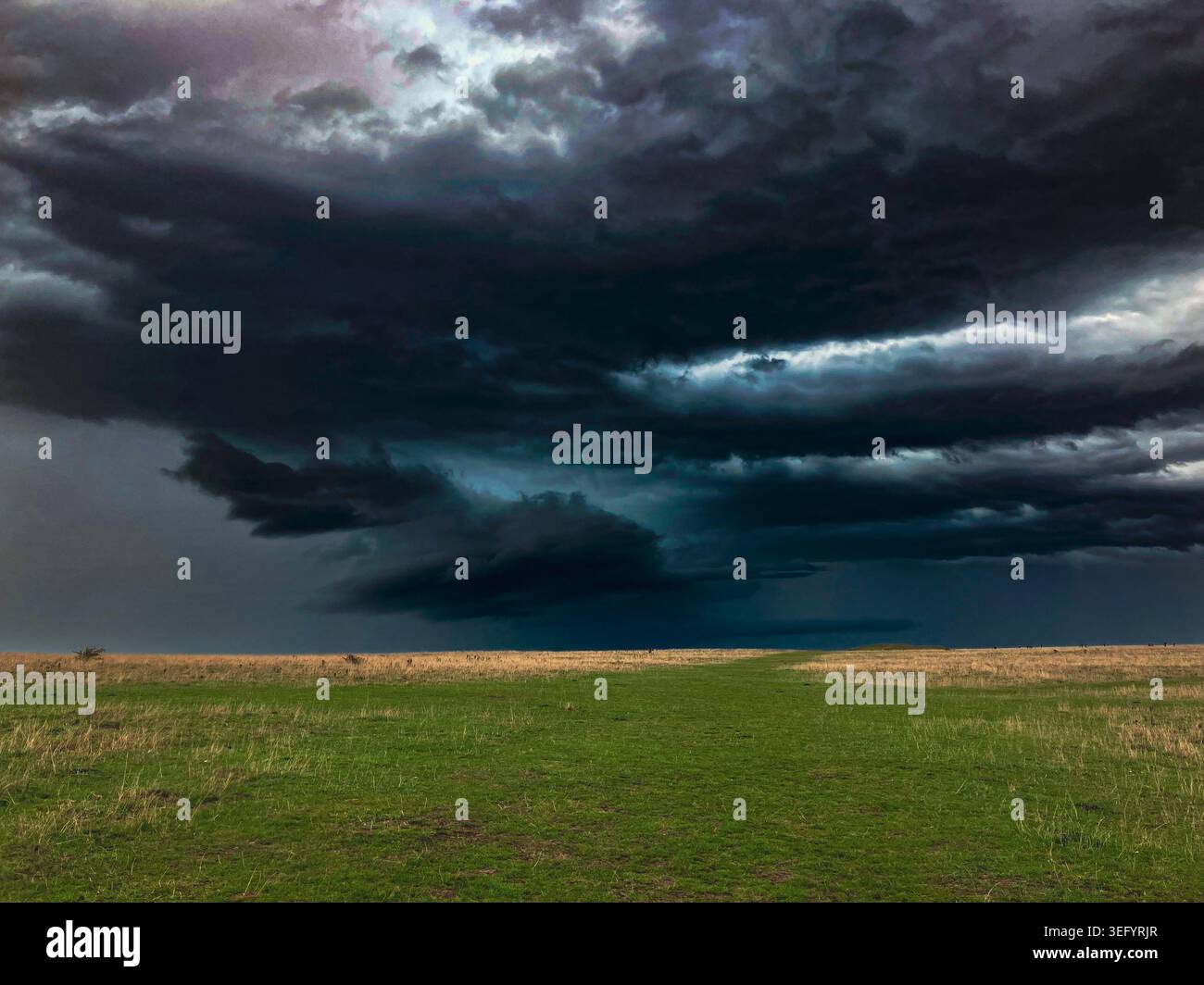 Storm clouds gather over a green landscape.  A thunderstorm is approaching with bad weather on the way. Stock Photo