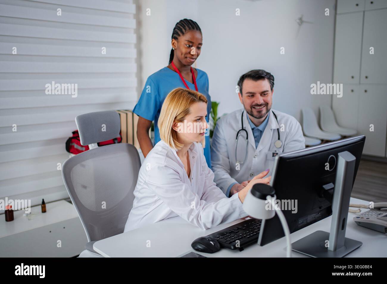 Diverse medical professionals collaborating on patient data using a computer Stock Photo
