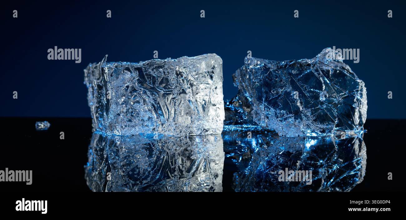 Broken ice with blue backlight on a black reflective background. Copy space. Stock Photo
