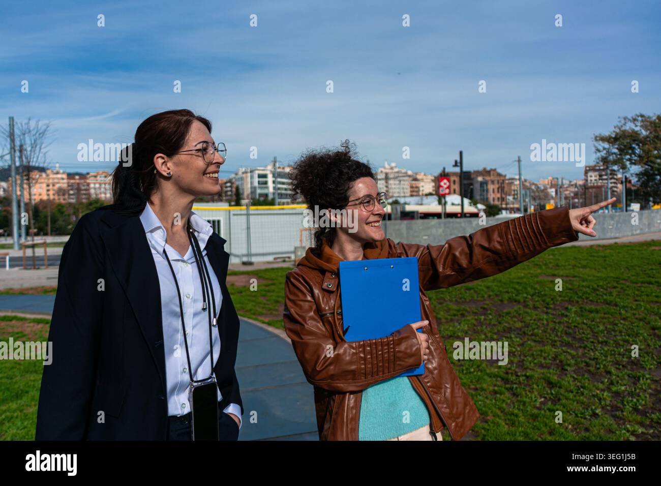 Businesswomen pointing looking ahead discussing project outdoors Stock Photo