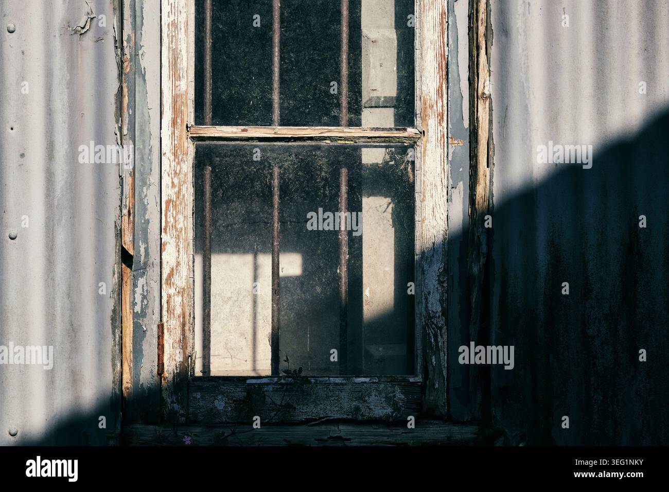 A rotten wooden window frame half cast in shadow. Stock Photo