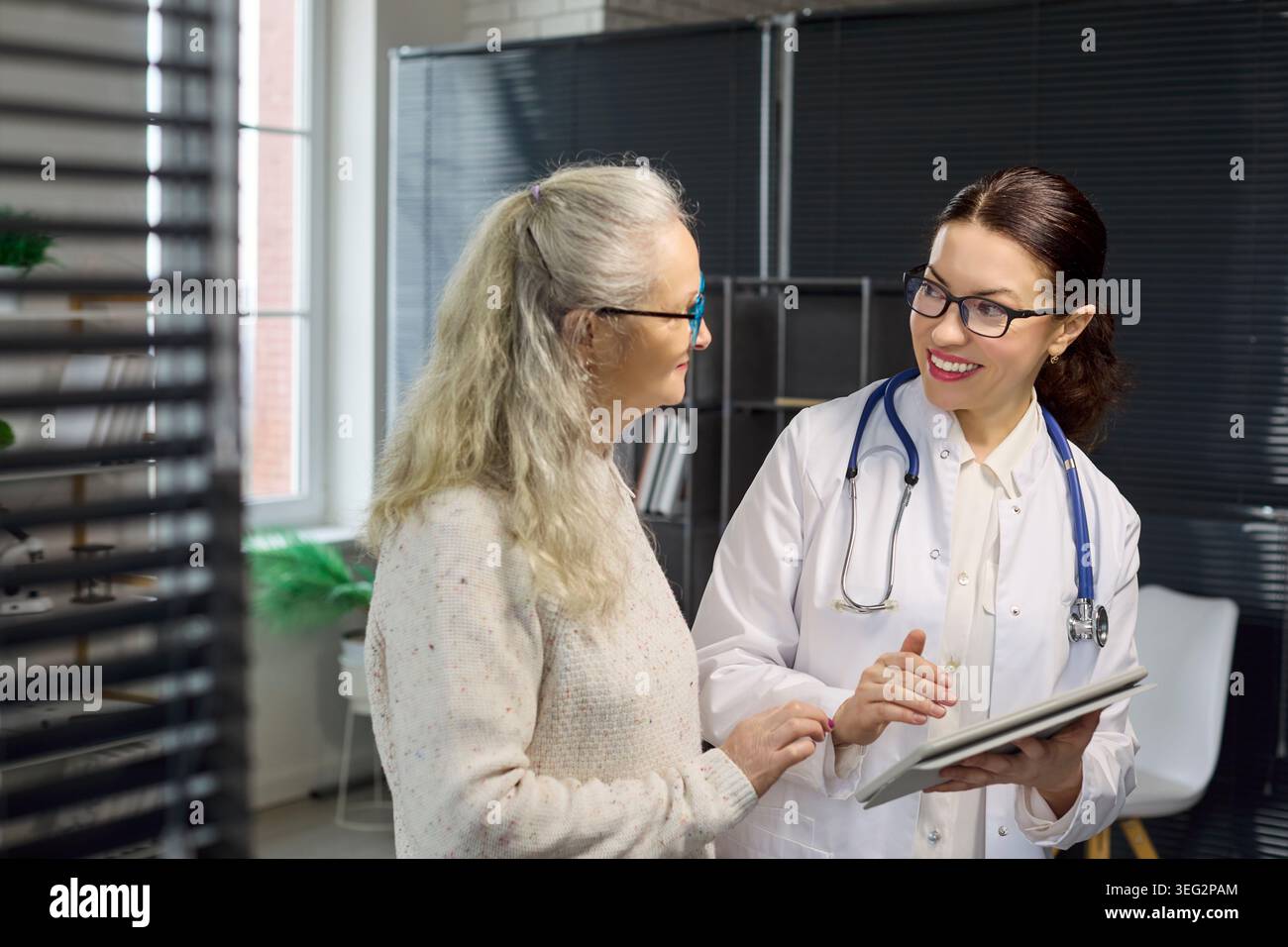 Smiling doctor discussing test results with senior patient using tablet computer Stock Photo