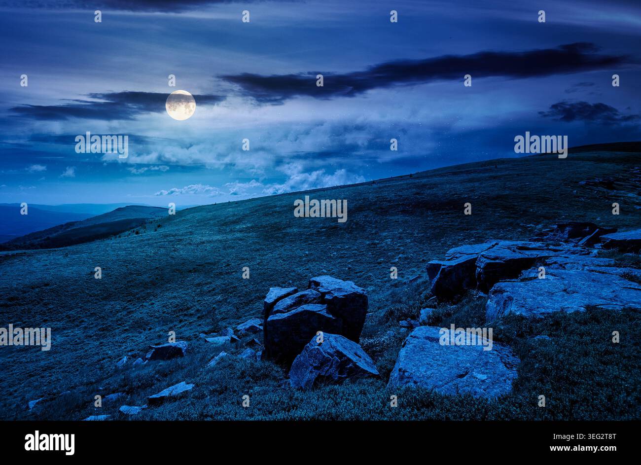 mountain landscape with alpine meadow in mysterious light at night. full moon over carpathian mountain scenery in summer. view in to the distant valle Stock Photo
