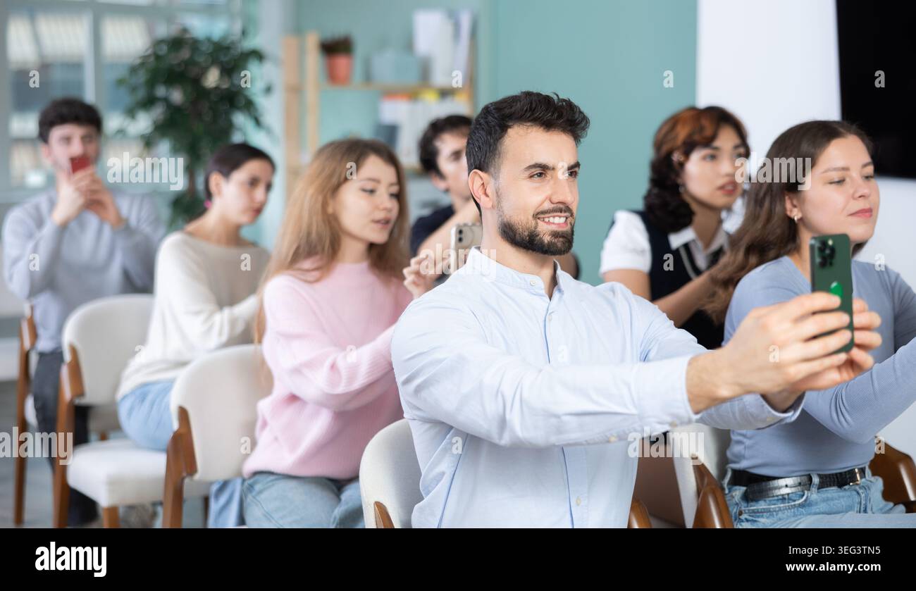 Students using mobile phones to scan QR code during interactive lesson Stock Photo
