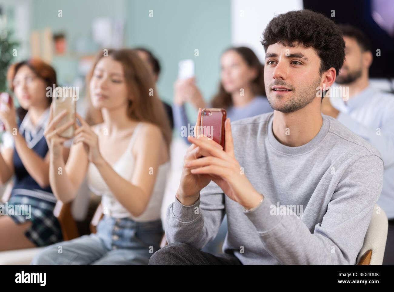 Young guy using mobile phone to scan QR code during interactive lesson Stock Photo