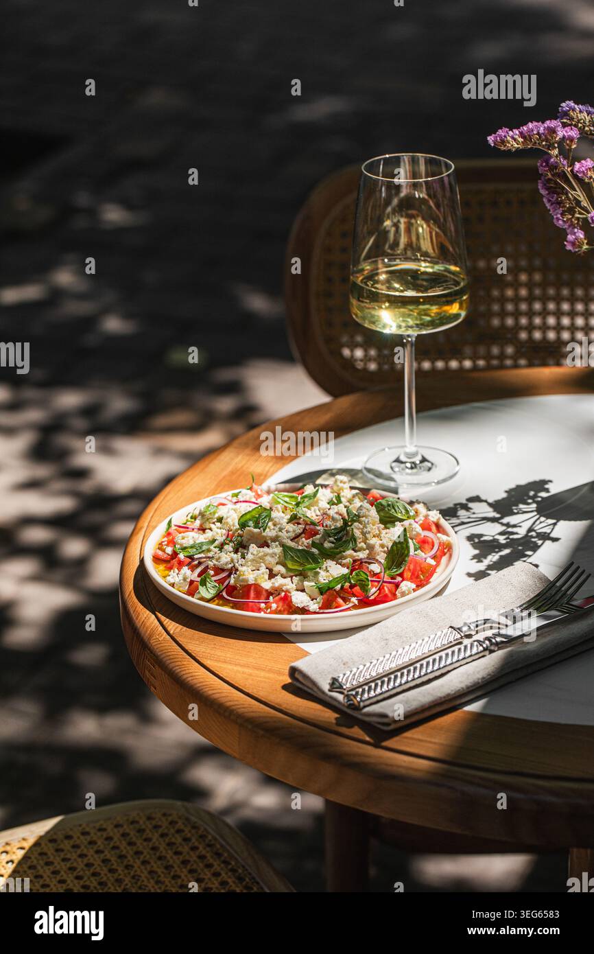 Mediterranean salad with wine on sunny table Stock Photo