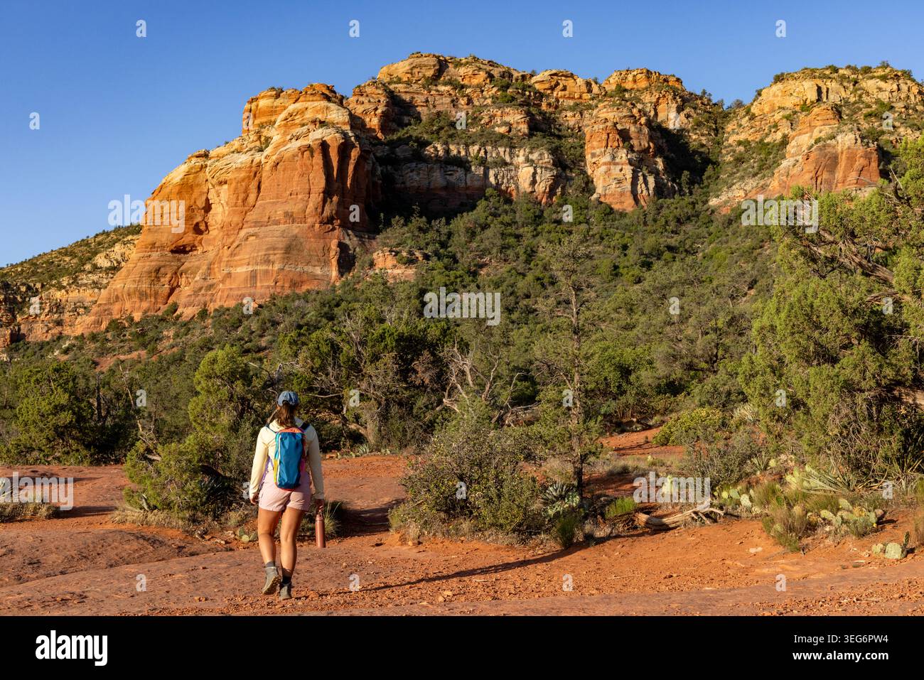 Lone woman hiker walking away towards rugged high desert brush Stock Photo