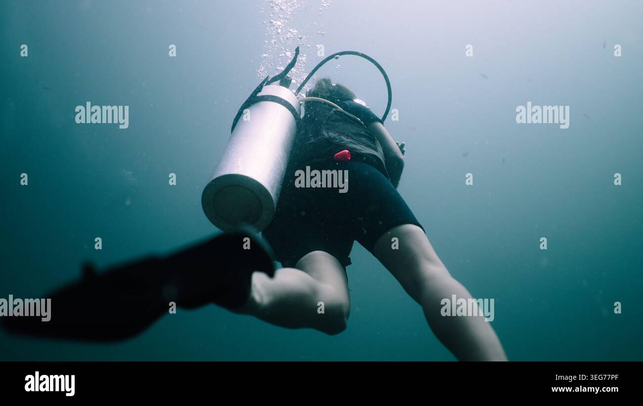 Scuba diver ascending in clear ocean water during an underwater ...