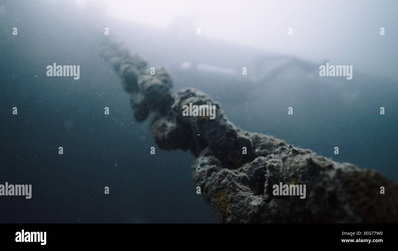 Rusted anchor chain in deep blue ocean connecting surface vessel to ...