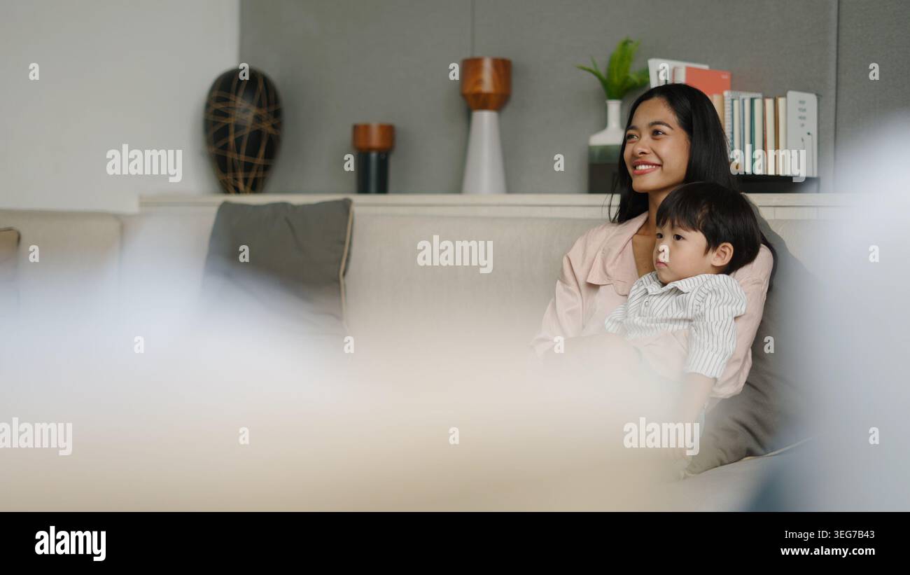 Mother And Child Sitting On Sofa Enjoying Comfortable Time Together At mother-and-child-sitting-on-sofa-enjoying-comfortable-time-together-at