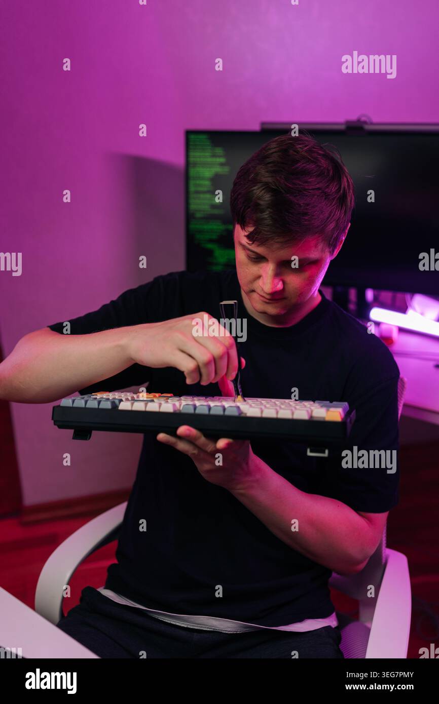 Portrait of young adult an focusing on removing keycaps from mechanical ...