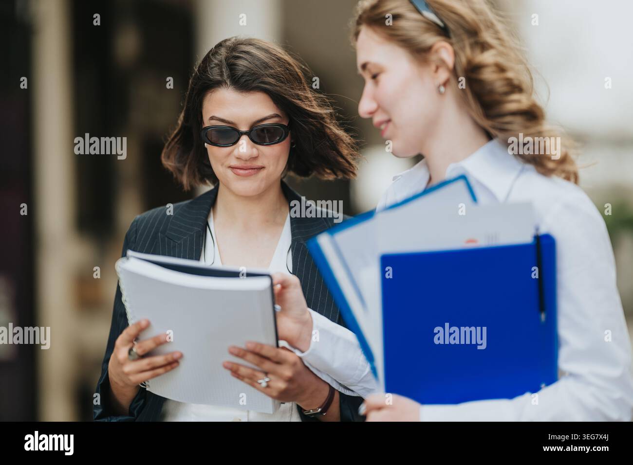 Two business people reviewing documents together outdoors discussing work and plans Stock Photo