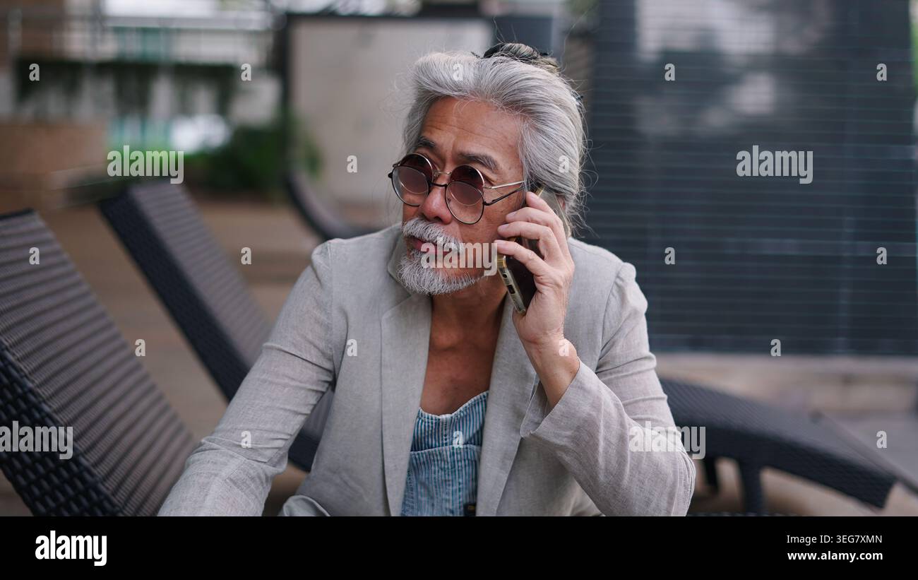Senior asian man talking on smartphone, communicating, connecting while relaxing Stock Photo