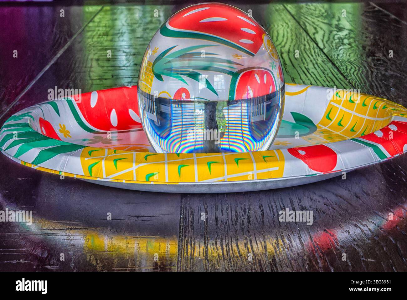 A solid glass ball on a dark surface captures reflected light. Stock Photo