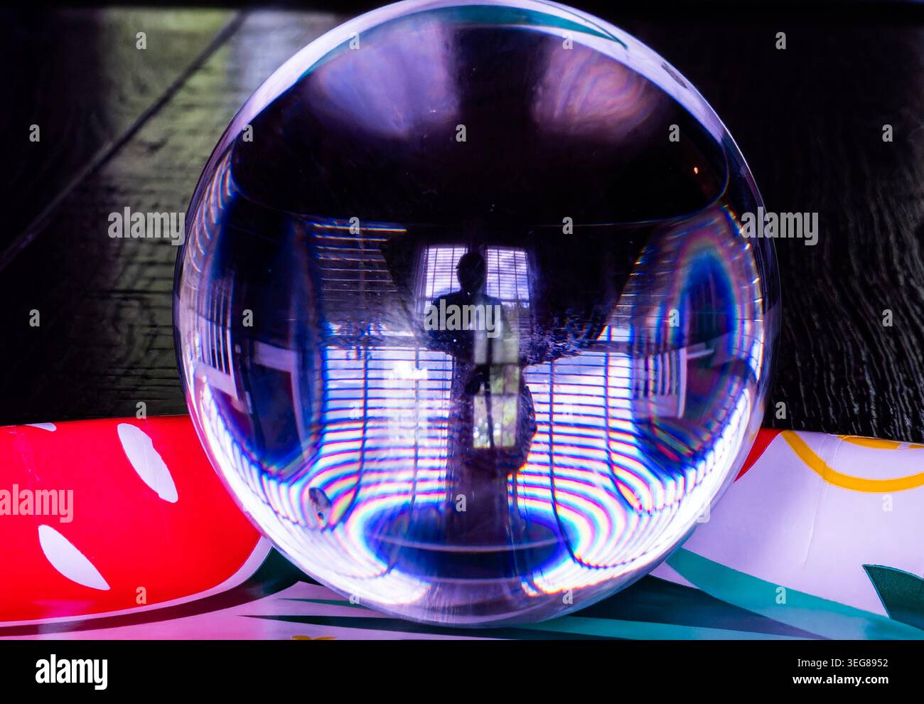 A solid glass ball on a dark surface captures reflected light. Stock Photo