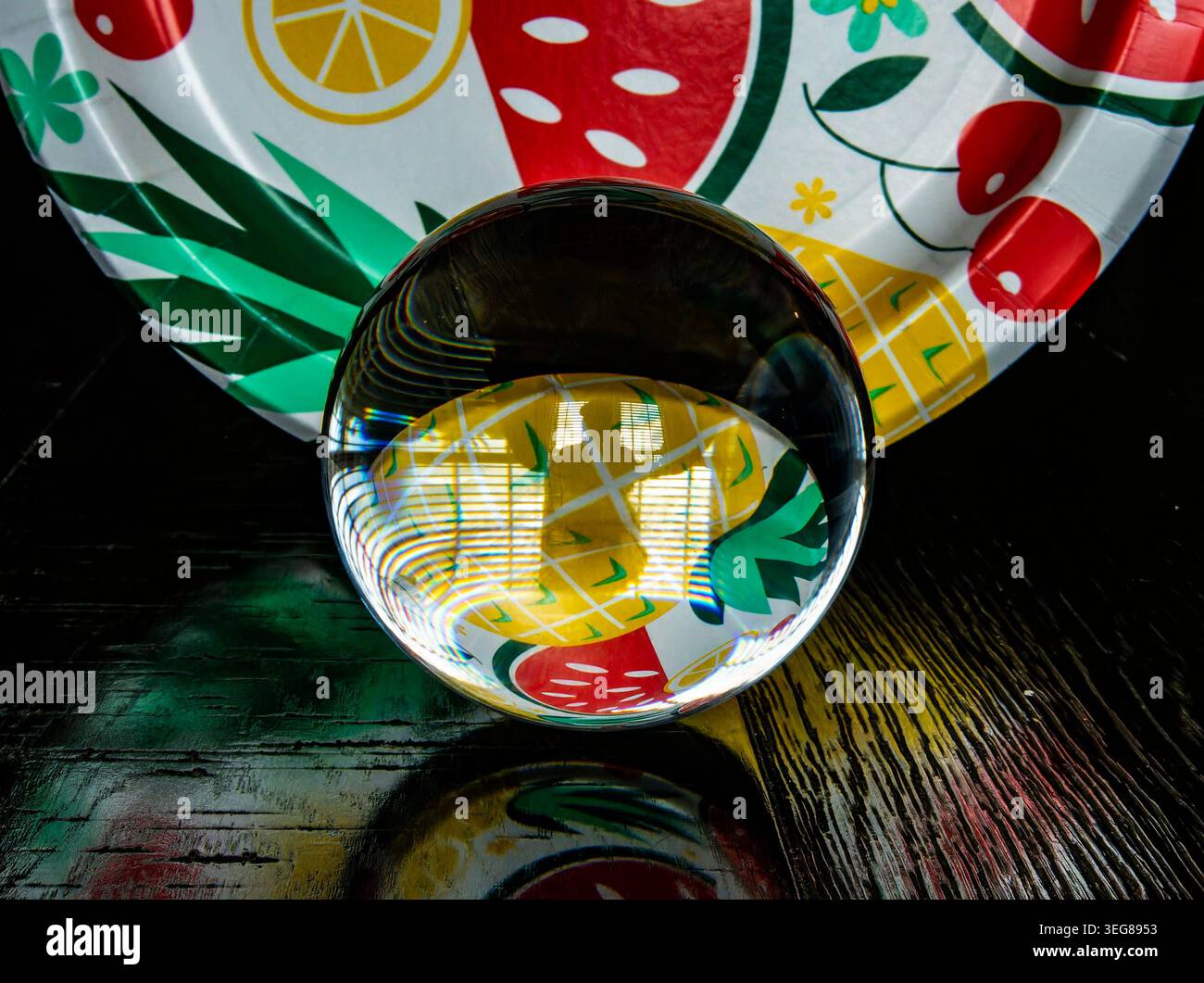 A solid glass ball on a dark surface captures reflected light. Stock Photo