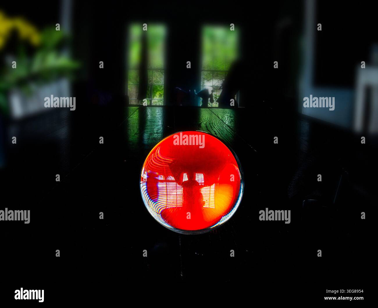A solid glass ball on a dark surface captures reflected light. Stock Photo