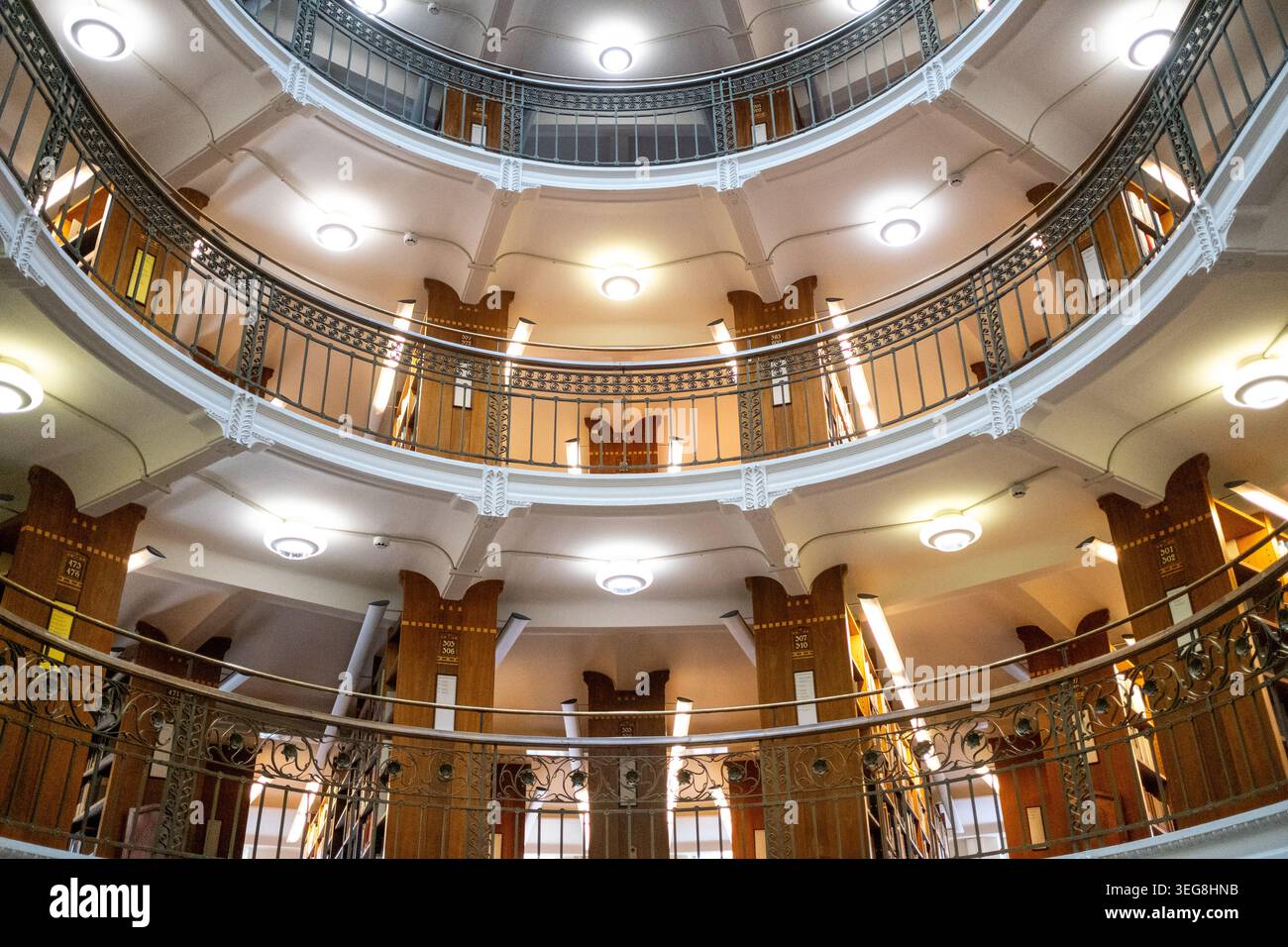 A multi level circular book hall with decorative iron railings rises ...