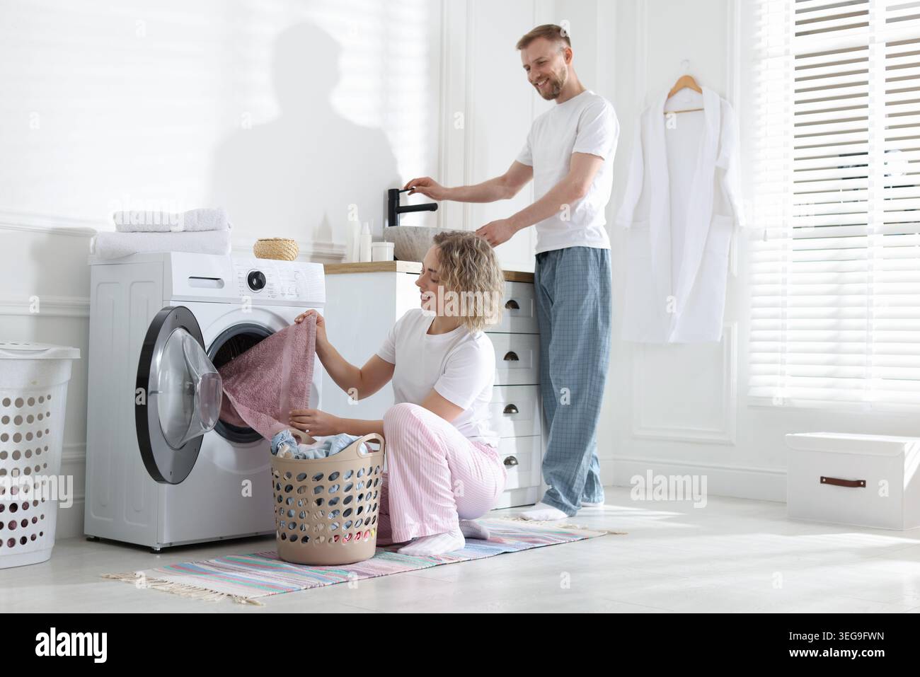 Happy couple doing laundry together at home Stock Photo