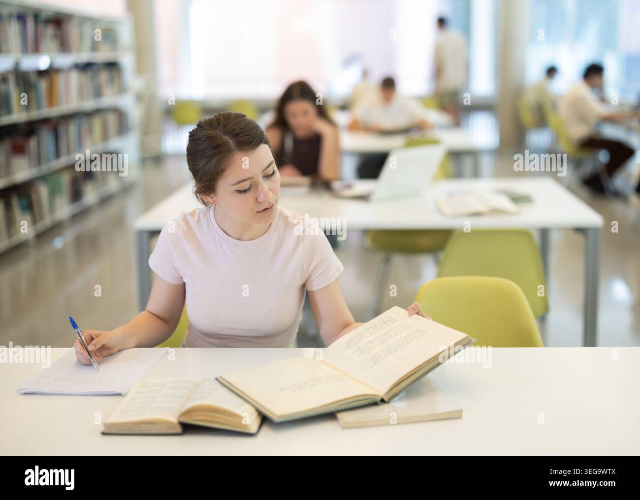 Female student sitting at table and writing Stock Photo