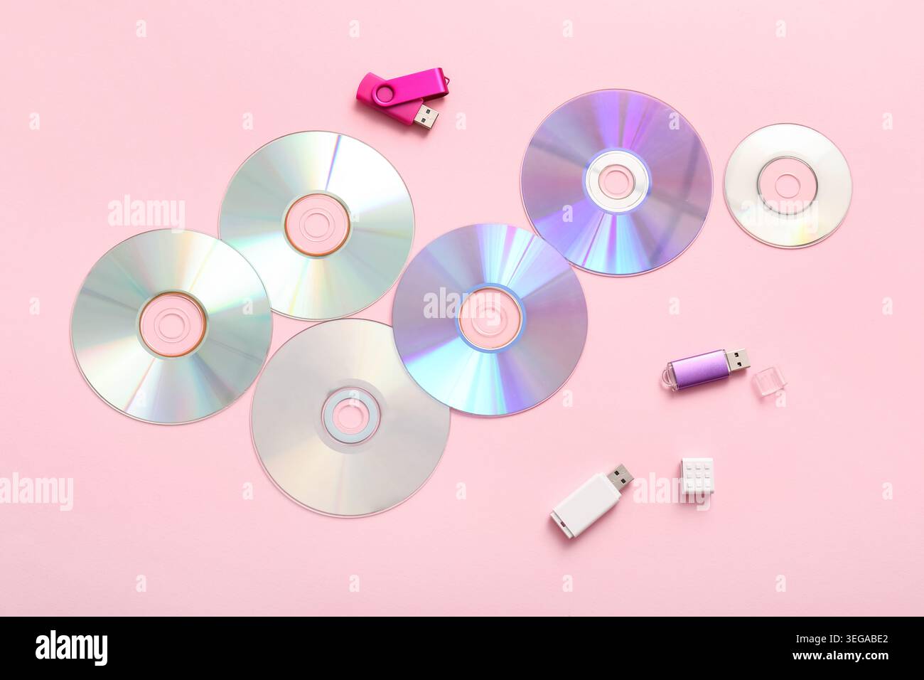 CD disks and USB flash drives on pink background Stock Photo