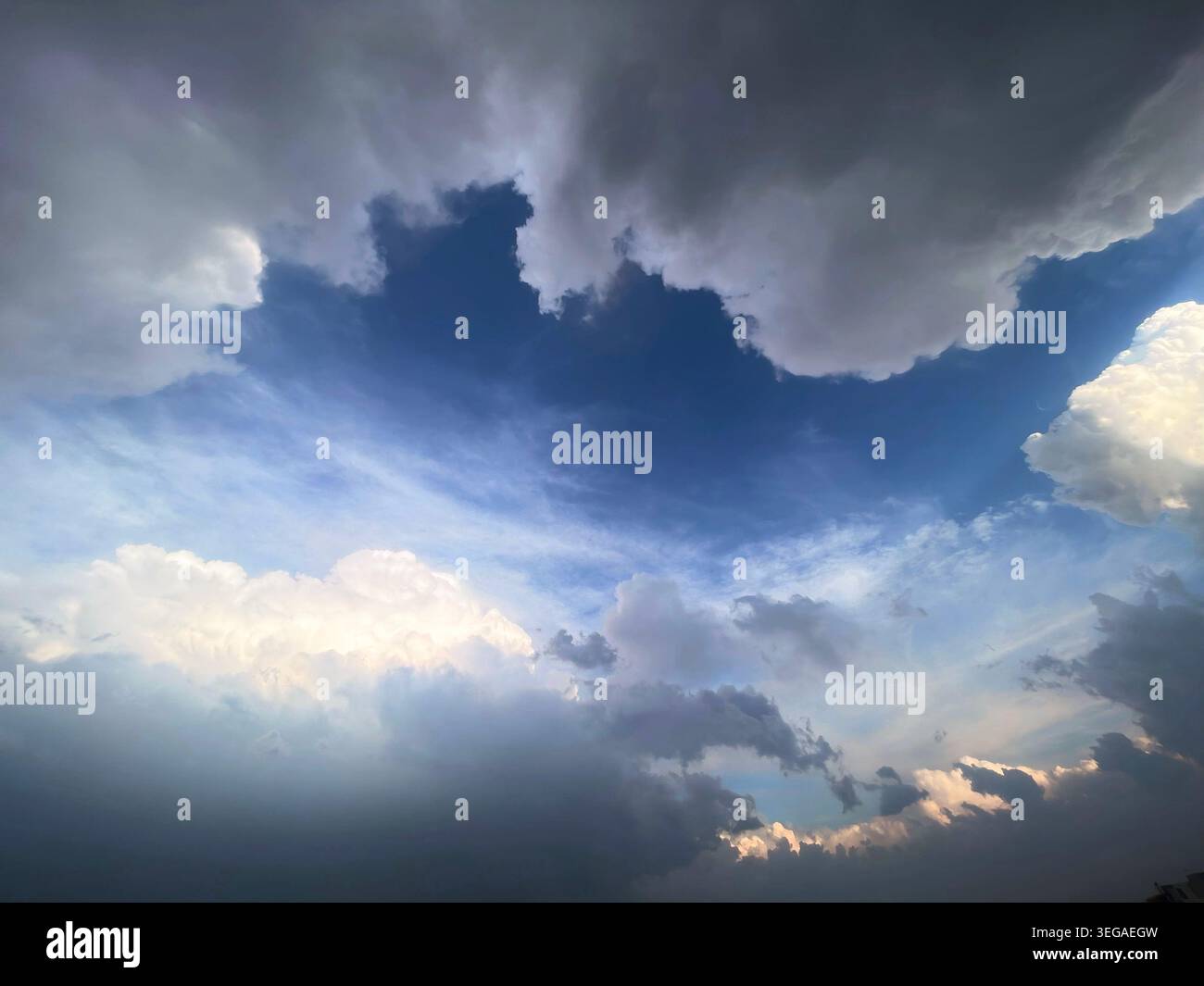 Dramatic Cloudscape with Blue Sky Opening and Sunlit Storm Clouds Background Stock Photo