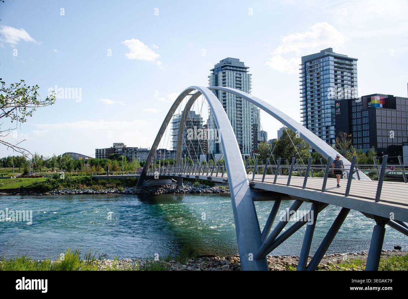 Modern pedestrian arch bridge spanning across the blue waters of the ...