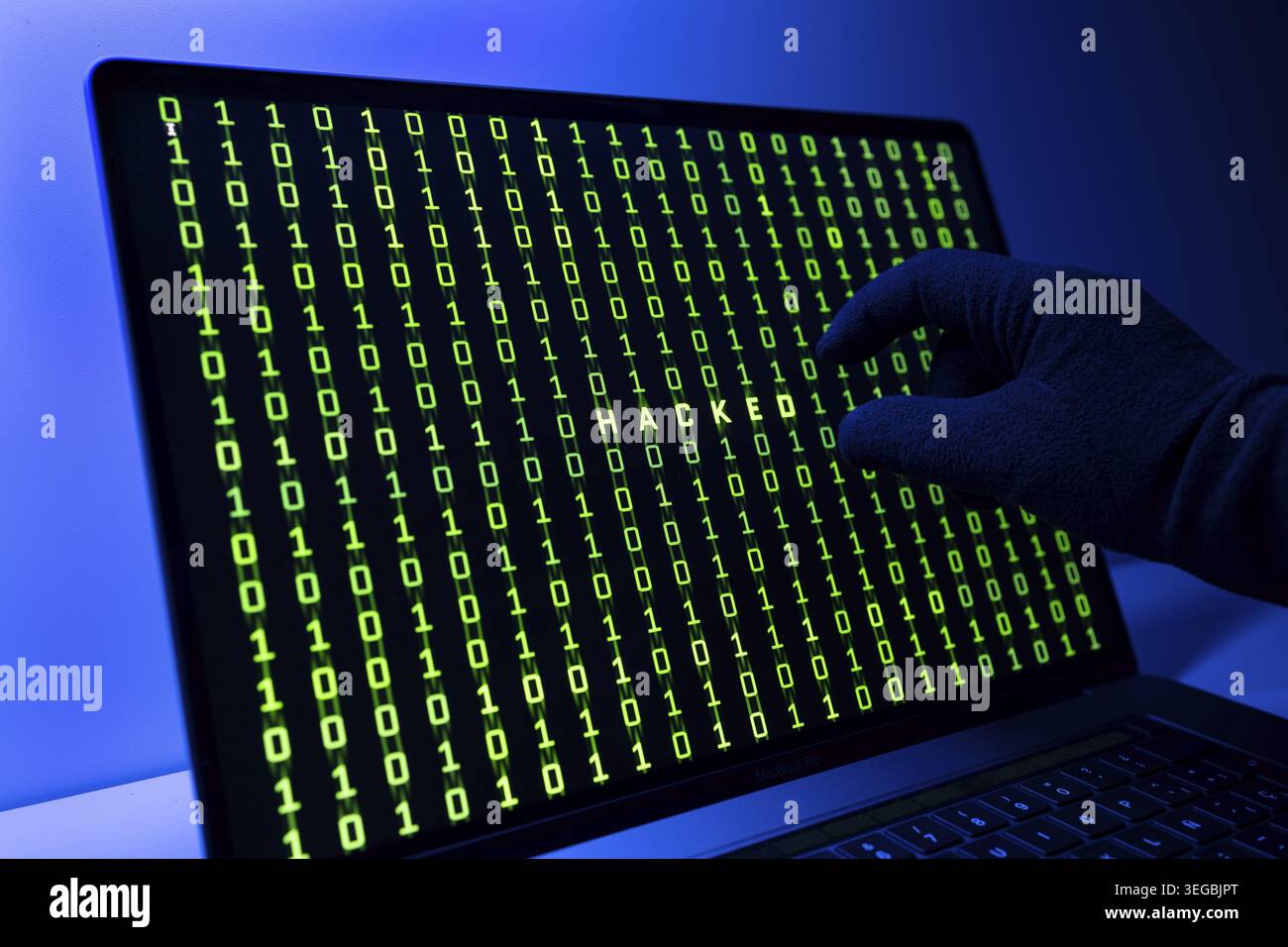 Hacked or hacking computer concept. Gloved Hand, Binary code and hacked word on laptop computer screen Stock Photo