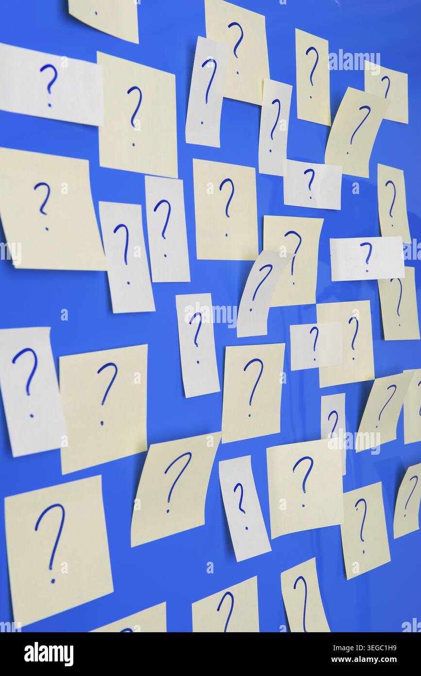 Memo sheets on the wall with many question marks Stock Photo