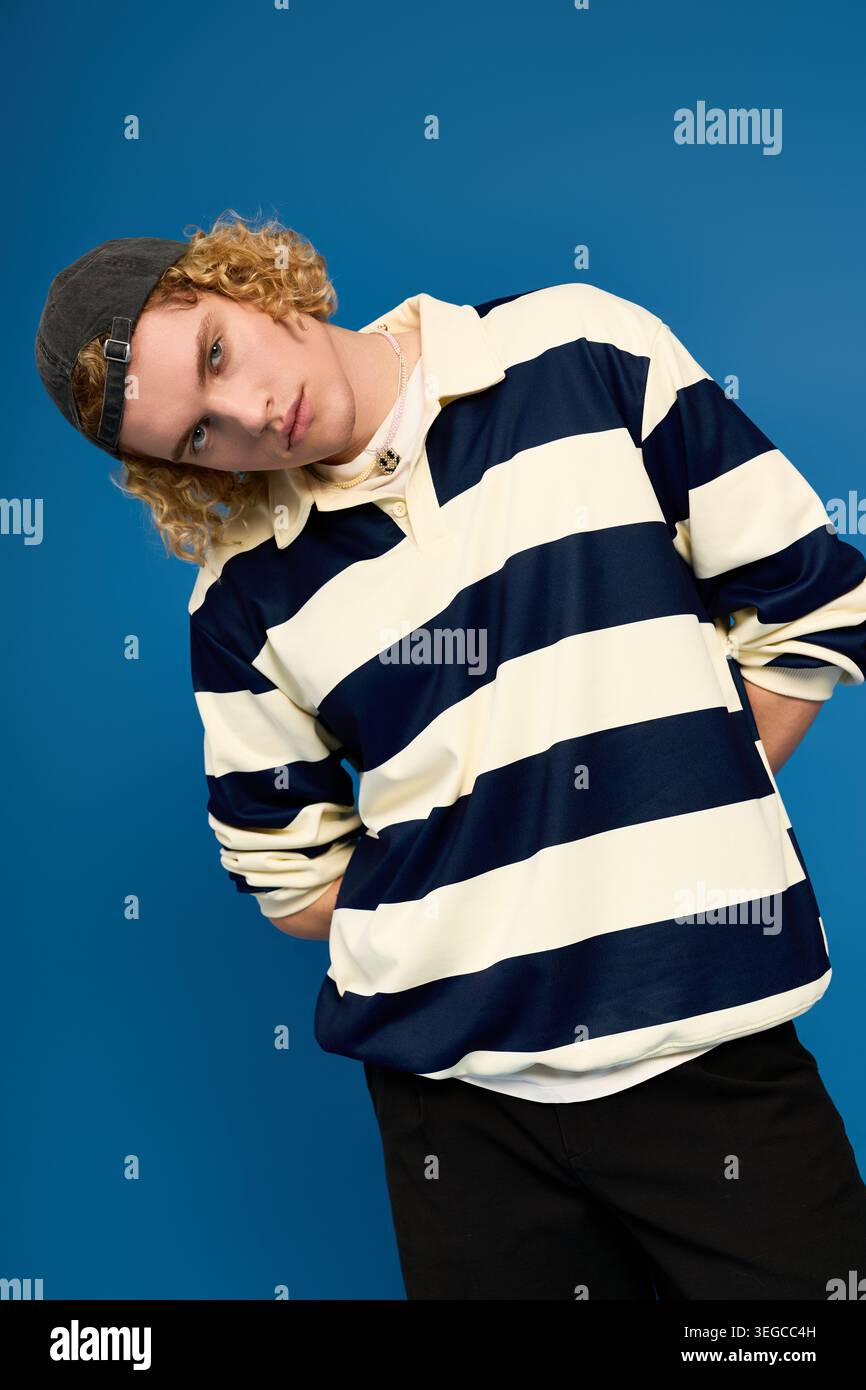 Blonde, curly haired guy showcases his unique fashion in a modern studio environment. Stock Photo