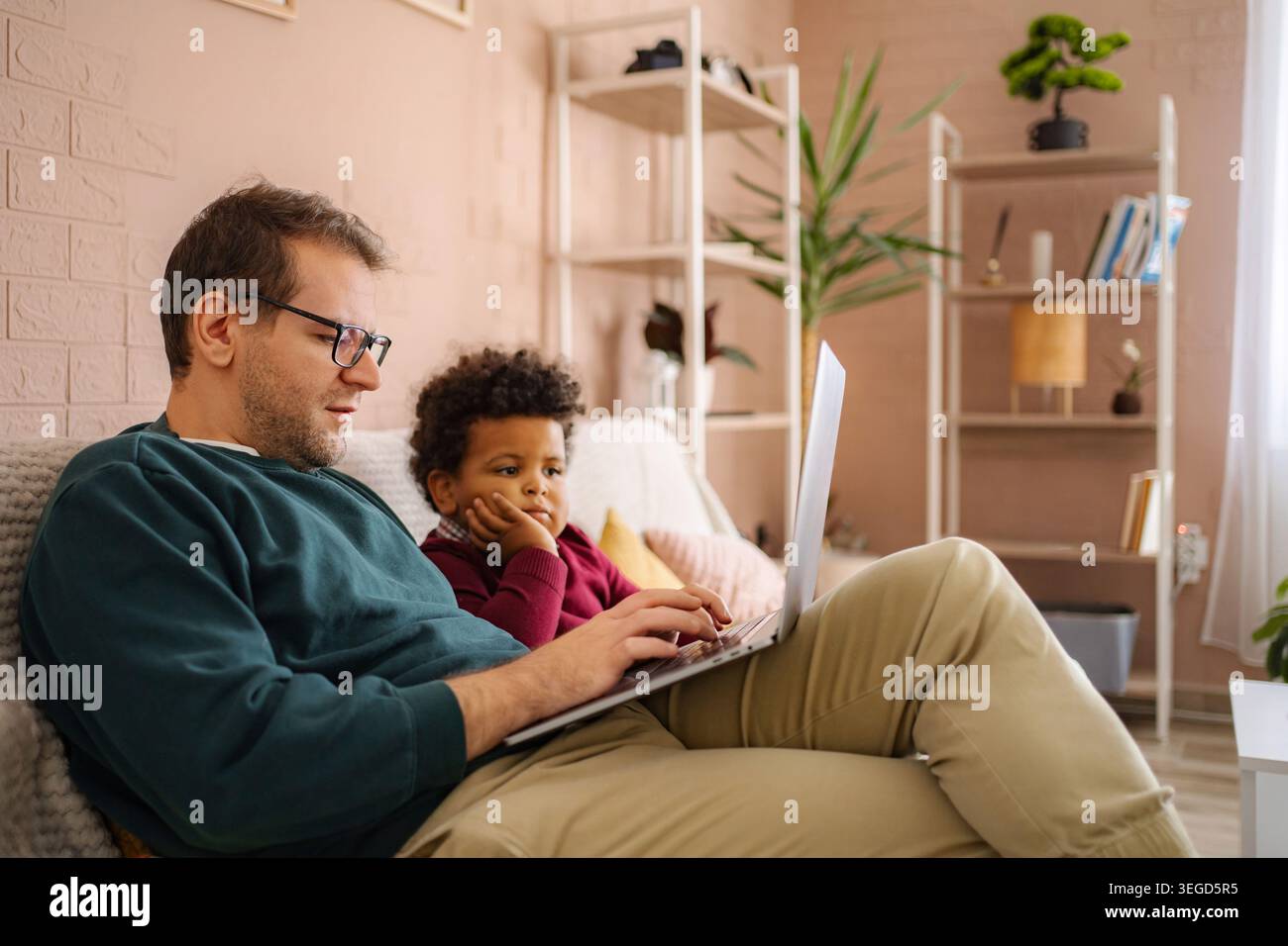 Father and son using laptop for remote work and learning Stock Photo