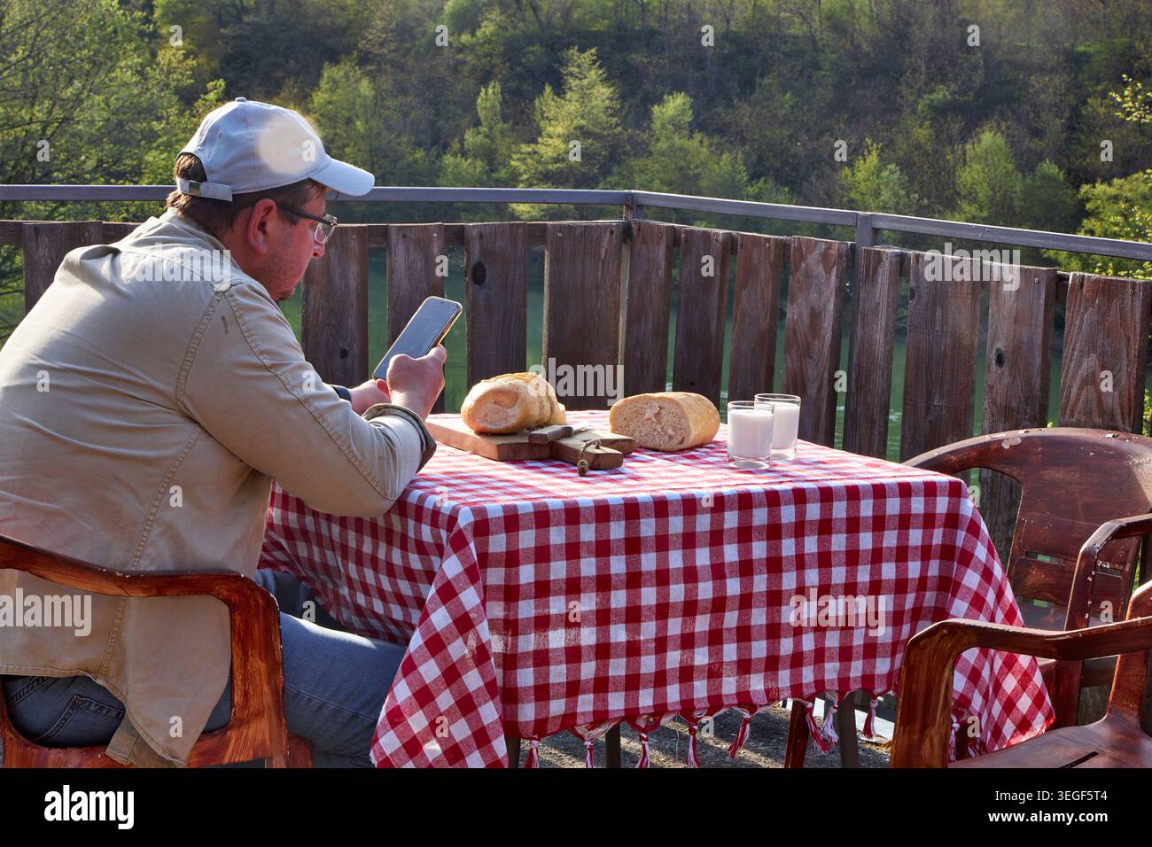 Man Using Smartphone During Rustic Countryside Breakfast Stock Photo