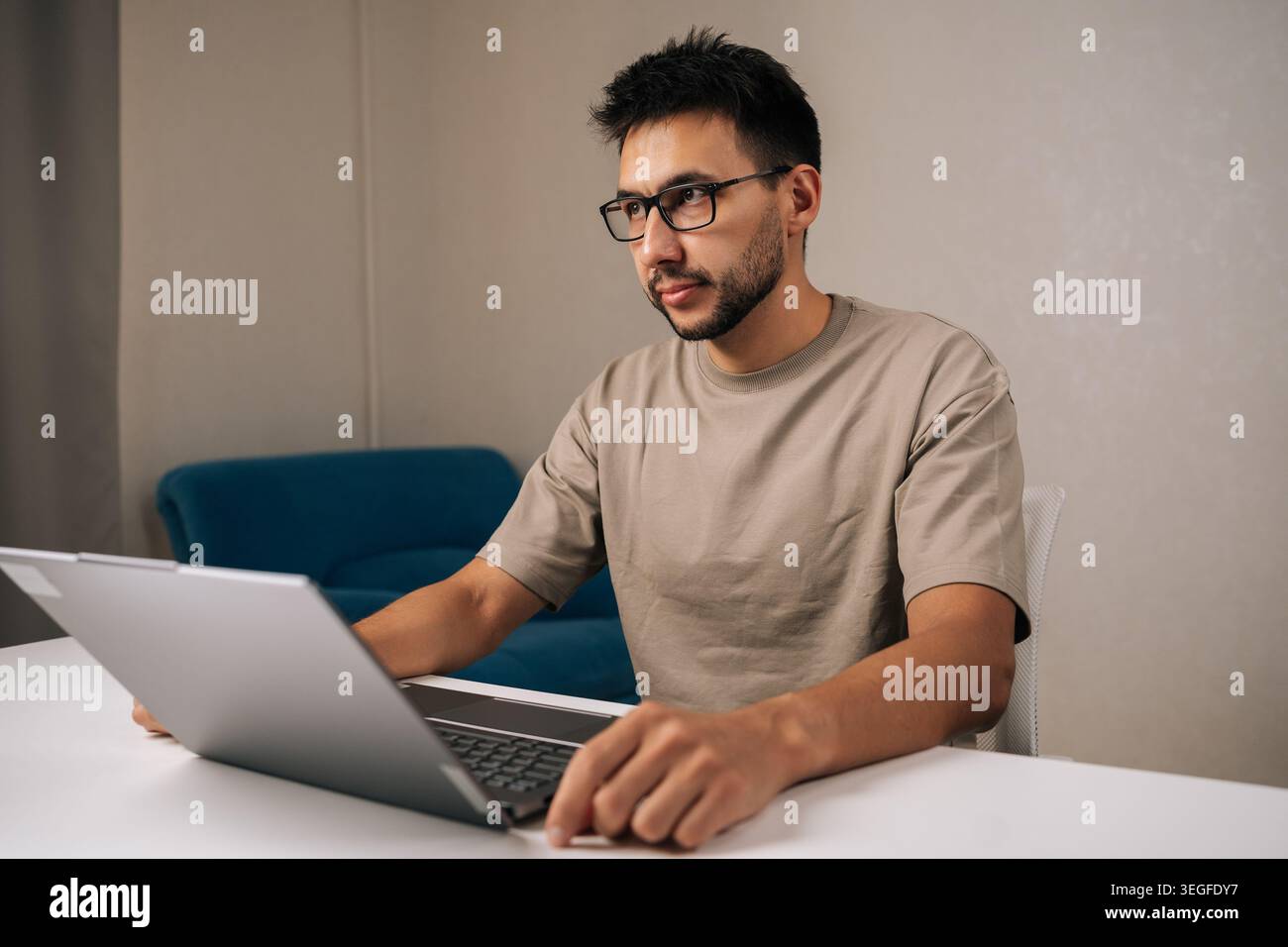 Pensive programmer male working typing code on laptop keyboard, showcasing process of software development and coding expertise. Stock Photo