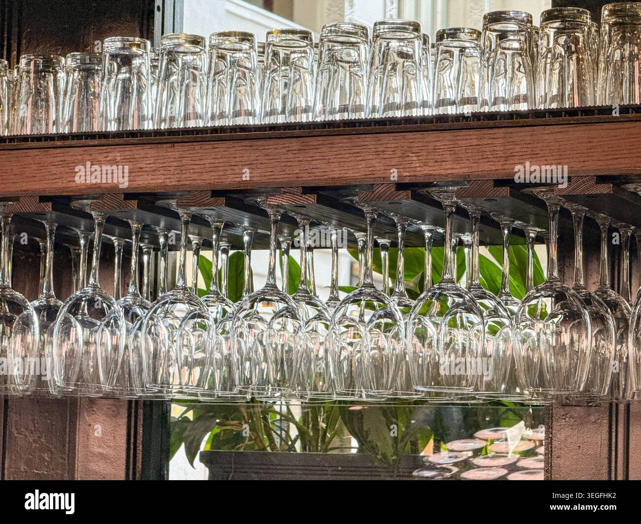 Empty wine glasses hanging from a rack in a bar Stock Photo