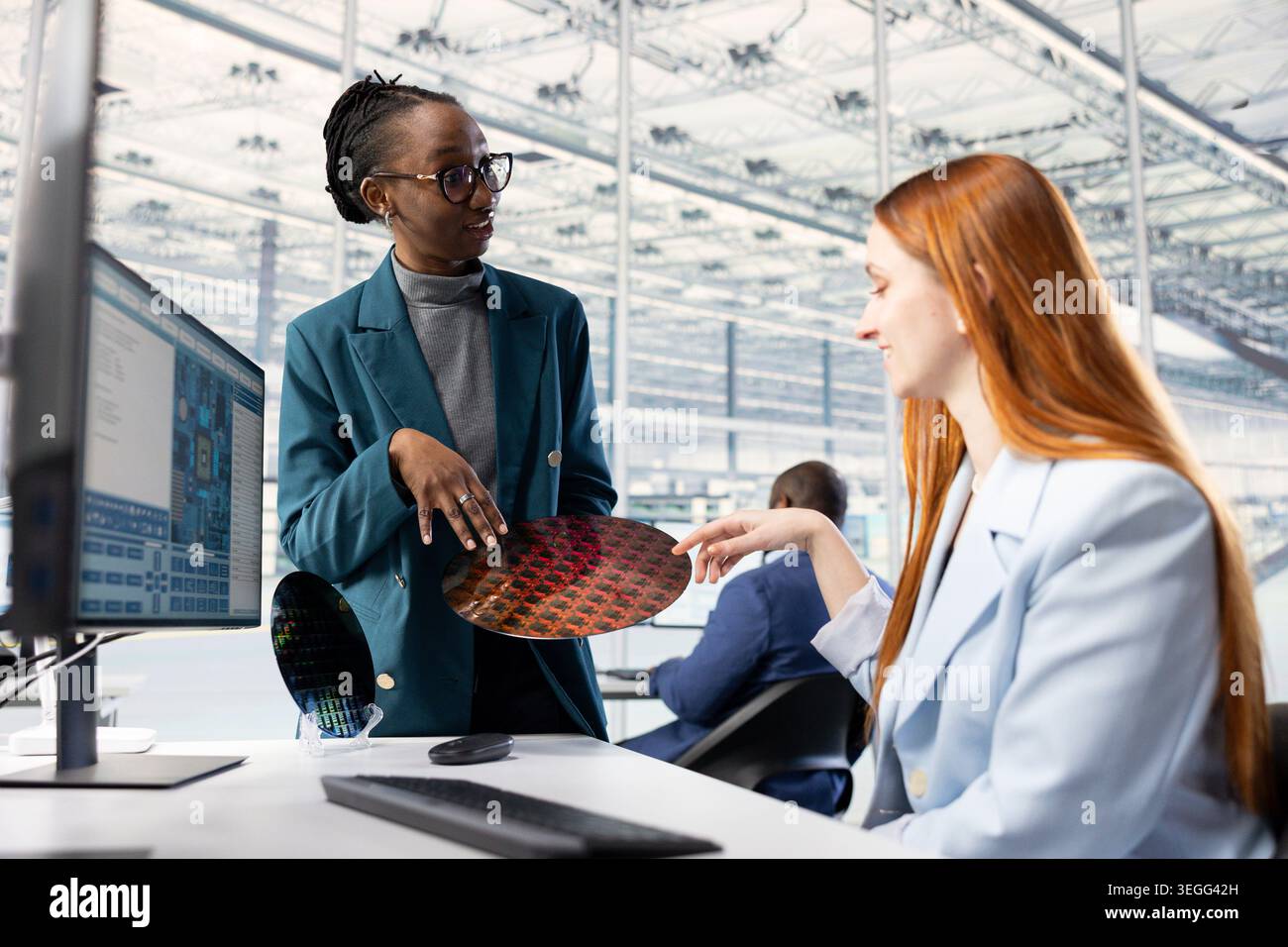 Women looking at silicon wafer, doing quality inspection in microchip factory RD lab. Female engineers examining intricate circuit patterns on semiconductor substrates in office Stock Photo