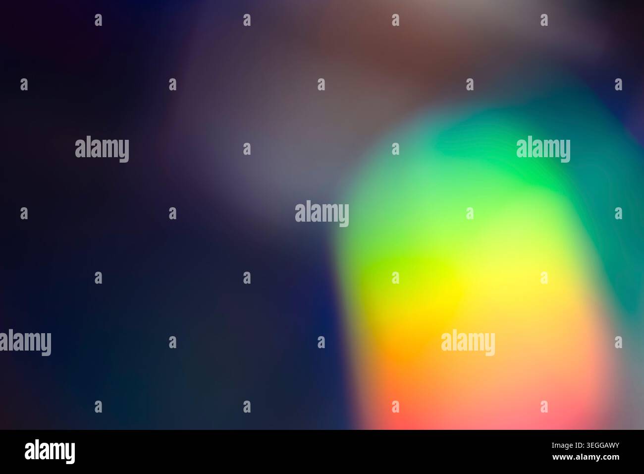 Abstract dark backdrop with a bright green and yellow blurred orb Stock Photo