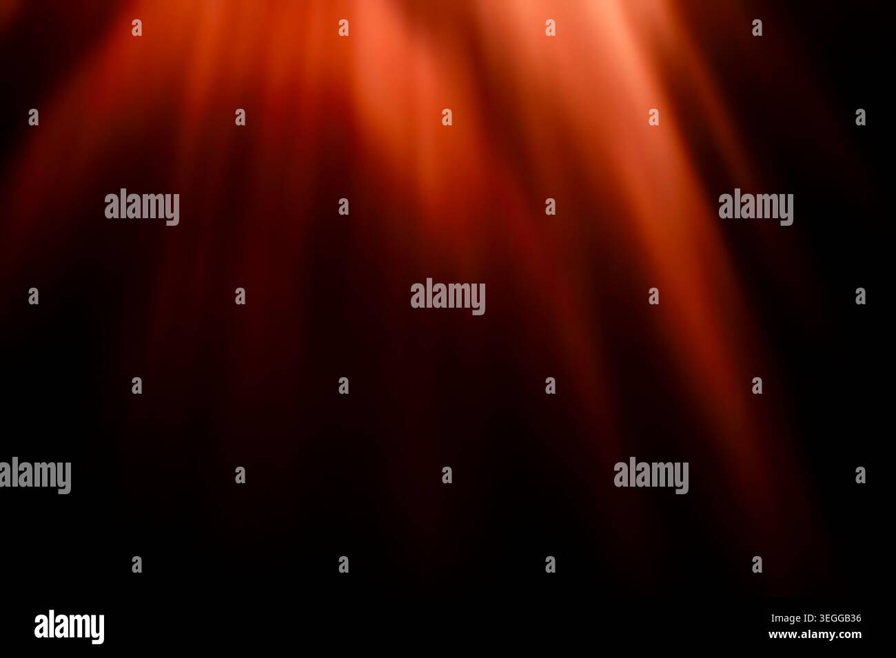 Intense red and orange glowing light rays falling on dark background Stock Photo