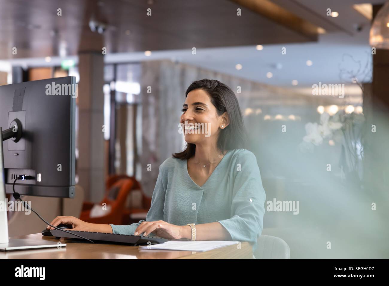 Smiling female receptionist working on computer at reception desk Stock Photo