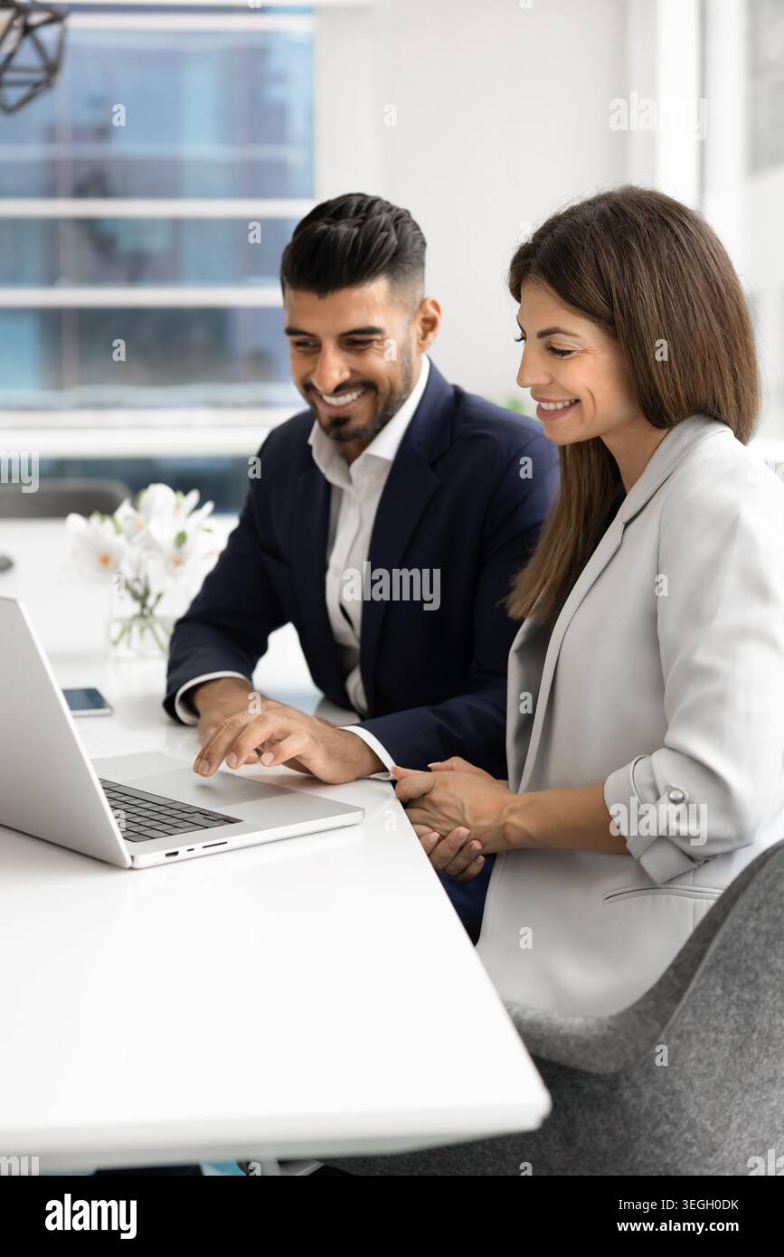 Coworkers collaborating on laptop in modern office Stock Photo