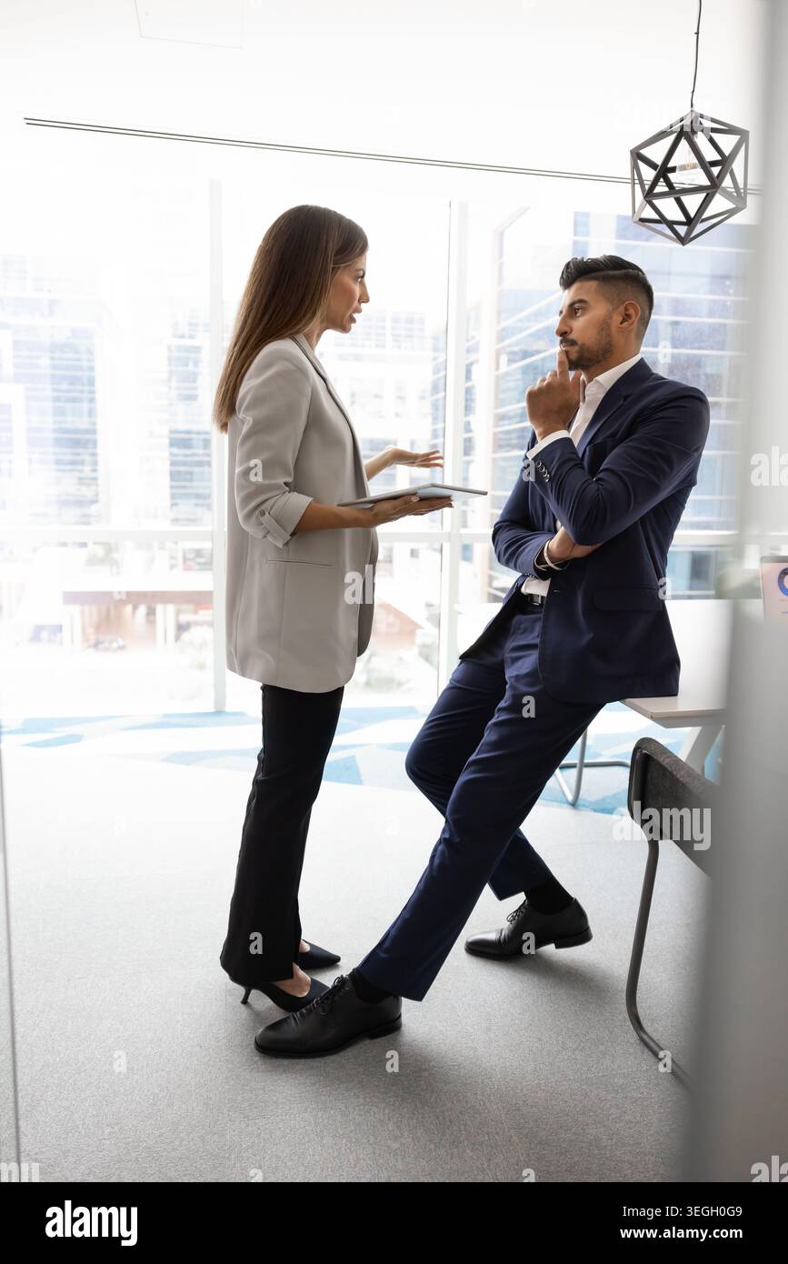 Coworkers discussing ideas in modern office space Stock Photo
