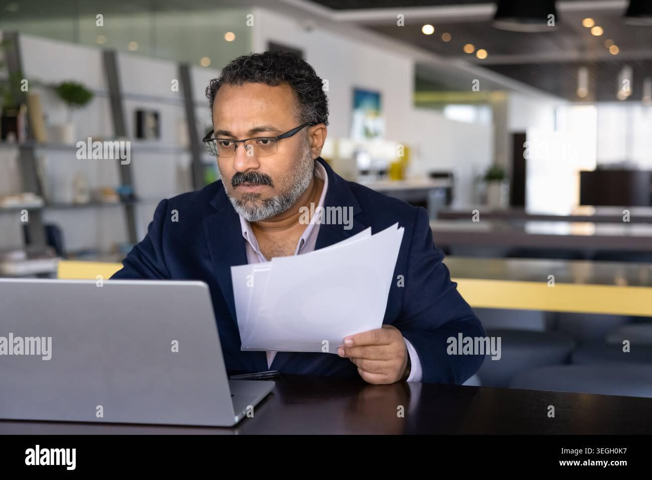 Businessman carefully reviewing performance reports in printed documents Stock Photo
